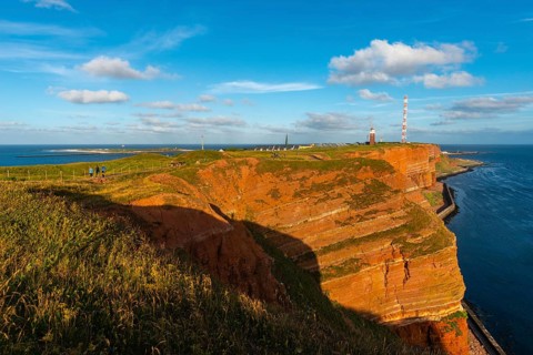 Red mottled sandstone cliff edge, Heligoland high sea island, North Sea, grass, lighthouse, radio