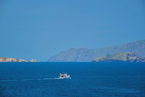 Greek fishing boat in blue waters of Aegean sea near Milos island, Greece, Europe