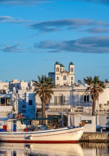 Fishing boats in the harbour at sunset, reflected in the sea, White Cycladic houses and church