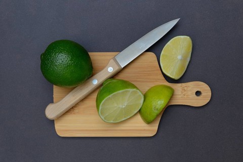 Halved limes on a chopping board with a kitchen knife