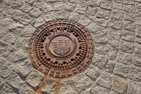 Manhole cover with city coat of arms, paving stones, soil, sewerage, Freiberg, Freiberg, Saxony,