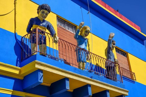 Footballer Diego Maradona, folk heroine Eva Perón and tango singer Carlos Gardel on a balcony,