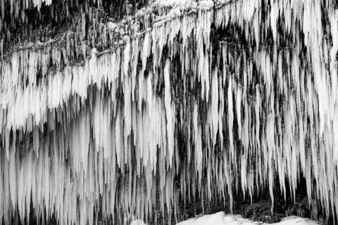 Icicles on the rock face at Skogafoss waterfall, black and white photo, Sudurland, Iceland, Europe