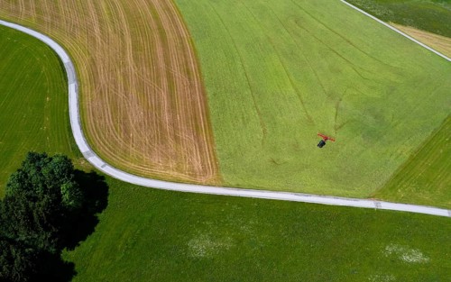 Drone view of a tractor turning hay in the field, Flachgau, Land Salzurg, Austria, Europe