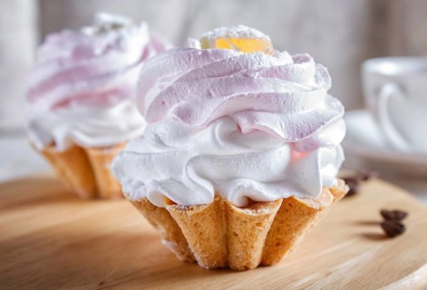 Cakes with whipped egg cream on wooden board, selective focus, close up