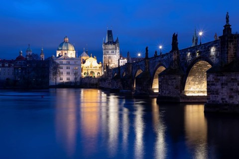 Charles Bridge with the Old Town Bridge Tower and the Church of the Holy Cross at the blue hour,