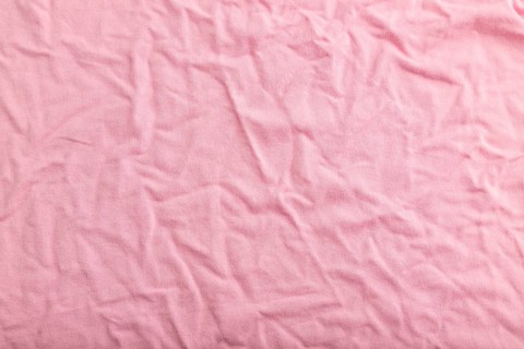 Fragment of pink cotton tissue. Top view, flat lay, natural textile background and texture