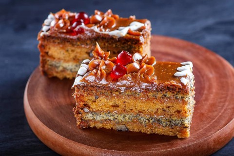 A piece of cake with caramel cream and poppy seeds on a wooden kitchen board. close up, selective