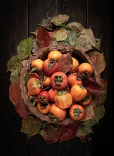 Fresh persimmon in a basket, with leaves, top view, no people