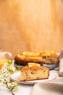 Orange cake and a cup of coffee on a white wooden background and linen textile. Side view, copy