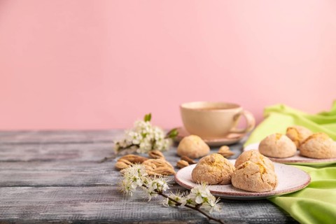 Almond cookies and a cup of coffee on a gray and pink background and green linen textile. Side