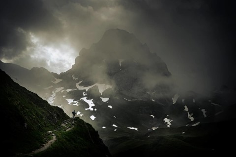 Mountaineer on a path with summit in the morning light and dramatic clouds, Lech,