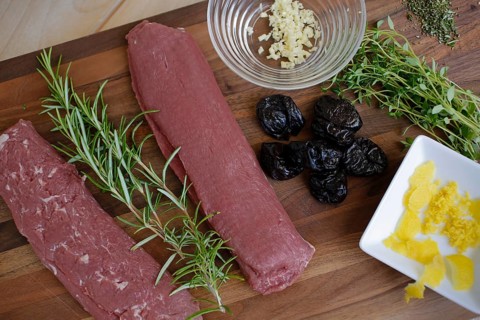 Swabian cuisine, preparation of lamb with prunes, raw lamb, rosemary, herbs, sliced garlic, lemon