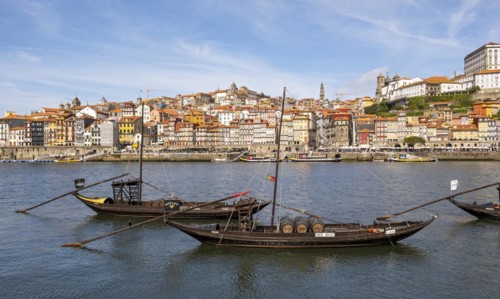 Old boats line the Douro River, with the charming Ribeira district in the background, Porto,