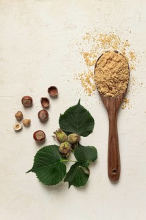 Wooden spoon with hazelnut flour, top view, no people, on a white table