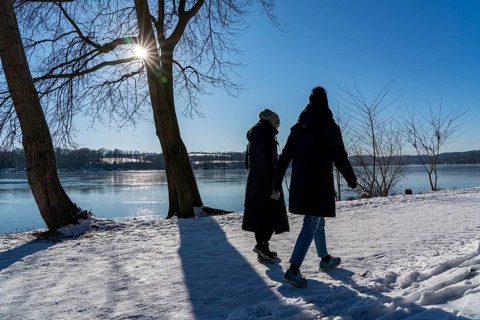 Winter in the Ruhr area, Lake Baldeney, snow-covered, partly frozen lake, walkers on the lakeside