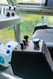 Control unit with a blue button and two levers in front of a window front, Hermann Hesse Bahn track
