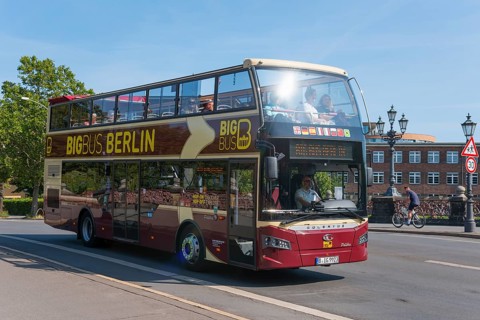 A red Berlin sightseeing double-decker bus on a street, full of tourists, double-decker bus,