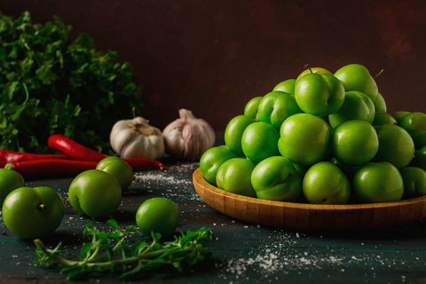 Tkemali, green cherry plum, with ingredients for sauce, cilantro, mint, hot pepper, garlic, on a