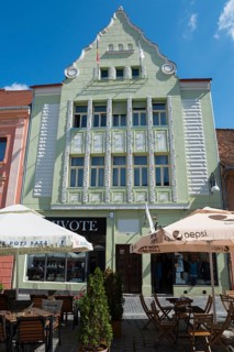 Historic Art Nouveau building in pastel green with café on the ground floor under a blue sky, town