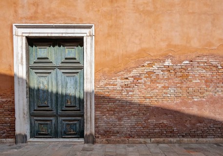 Red house facade with large green door, peeling plaster on brick wall, Venice, Veneto, Italy,