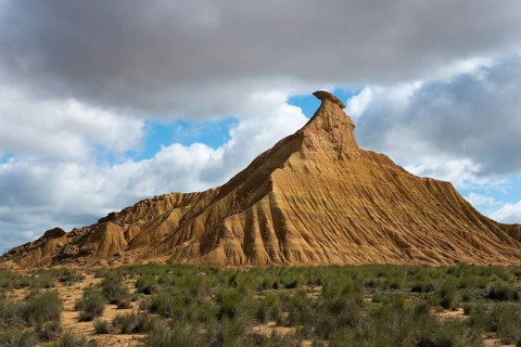 Lonely hilltop with characteristic shapes rises magnificently under a partly cloudy sky in the