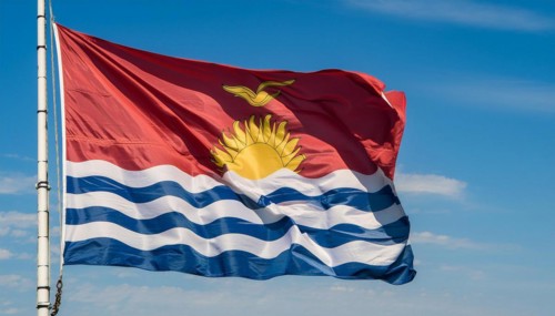The flag of Kiribati, Polynesia, flutters in the wind, isolated against a blue sky