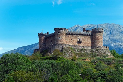 Medieval castle on a hill surrounded by nature with majestic mountains in the background, Castillo