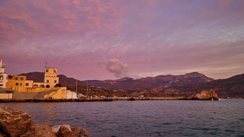 Romantic picture of the coast at dawn, with historic buildings on the shore and mountainous