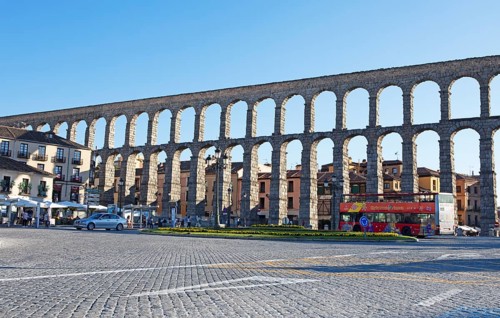Sightseeing bus at the Roman aqueduct in Plaza de Azoguejo, Segovia, province of Segovia, Castile