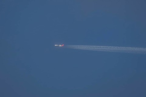 Boeing 747 jumbo jet aircraft in flight with a contrail or vapour trail in the sky, England, United