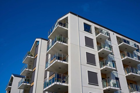 Modern residential building with several balconies and a façade under a clear blue sky, Molde,