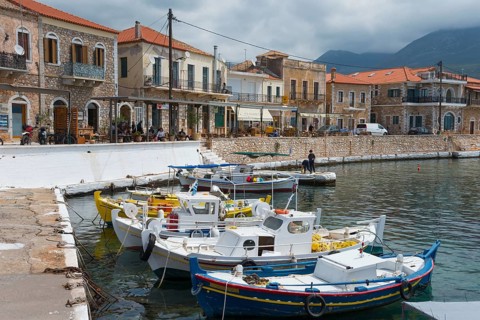 Small harbour with fishing boats in front of a row of traditional stone buildings on the coast with