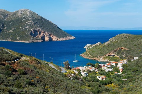 Small coastal village by the blue sea with surrounding green mountains and a peaceful atmosphere,