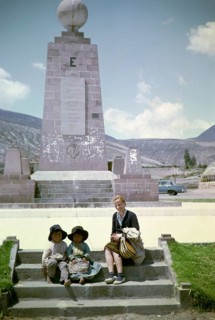 Tourist with local children at the equator monument from 1936, Ciudad Mitad del Mundo, Pichincha,