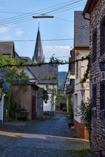 Alley, historic buildings, church tower of St. Nicholas, pointed roofs with slate slabs, lamp,