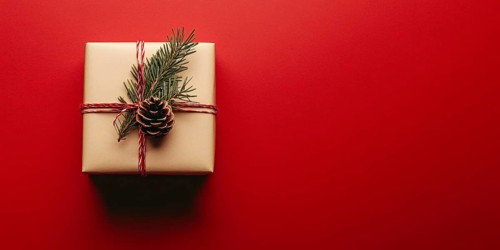 Banner with small Christmas gift box wrapped in graft paper on red background with copy space.