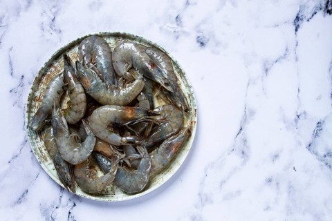 Fresh shrimp, laid out on a round plate, on a marble background, ready for grilling, seafood,