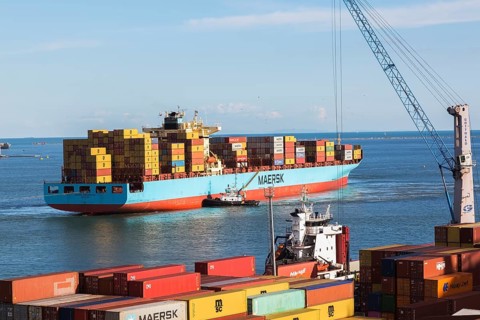 Maersk Serangoon cargo ship loaded with metal box shipping containers being guided by pilot boats