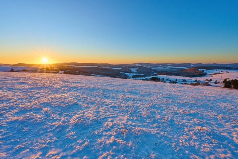 Snow-covered landscape at sunrise lying gently over the hills, winter, Wasserkuppe, Gersfeld, Rhön,