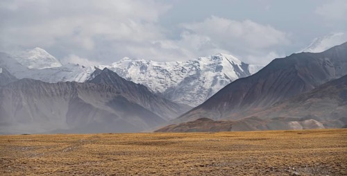 Glaciated, cloud-covered mountain peaks and golden meadows, Lenin Peak, Trans Alay Mountains, Pamir