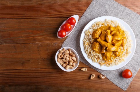 Rice with chicken curry sauce with cashew on brown wooden background. top view, copy space