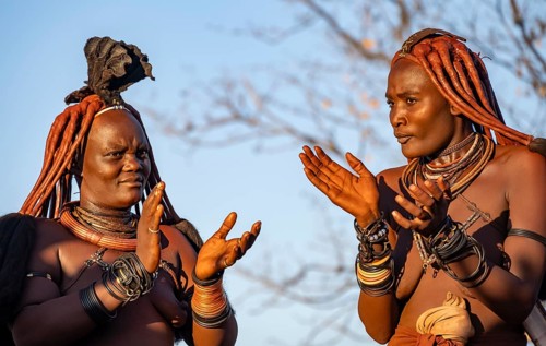 Traditional Himba woman clapping, music and dance, portraits, in the evening light, near Opuwo,