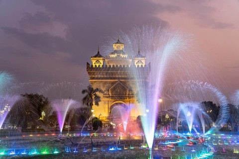 Colourfully illuminated fountain at Patuxai Victory Gate at dusk, capital Vientiane, Laos, Asia