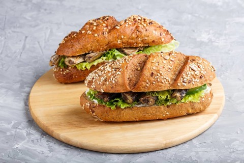 Sprats sandwiches with lettuce and cream cheese on wooden board on a gray concrete background. side