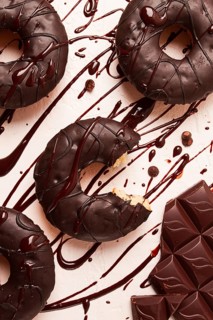 Donuts, in chocolate glaze, on a beige background, with liquid chocolate