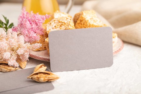 Gray business card with traditional turkish delight (rahat lokum) on white ceramic bowl on a gray