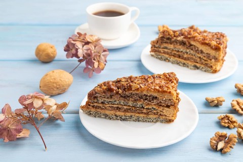 Walnut and hazelnut cake with caramel cream, cup of coffee on blue wooden background. side view,