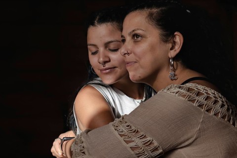 Portrait of deaf Latina mother hugging with young adult daughter