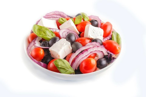 Greek salad with fresh cherry tomatoes, feta cheese, black olives, basil and onion isolated on